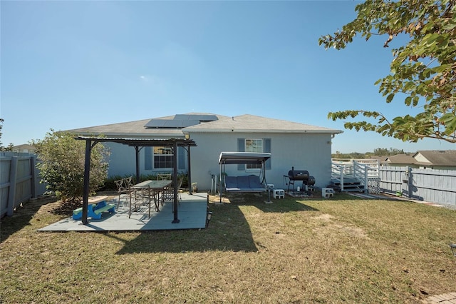 back of property featuring a patio area, solar panels, and a lawn