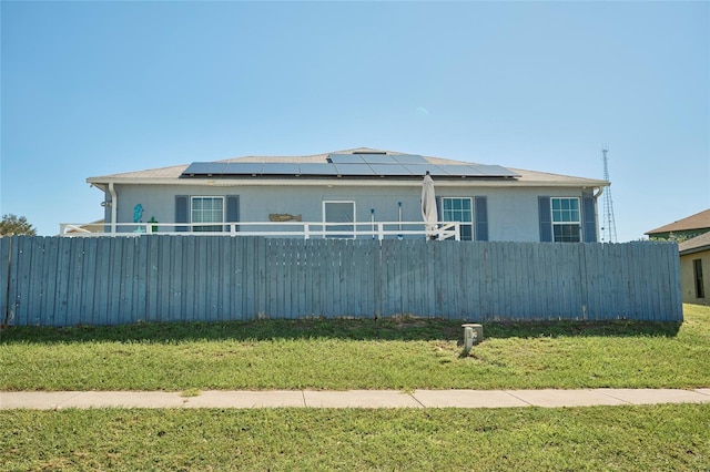 view of front facade featuring a front yard and solar panels