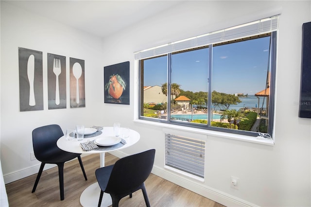 dining space with hardwood / wood-style flooring and a water view