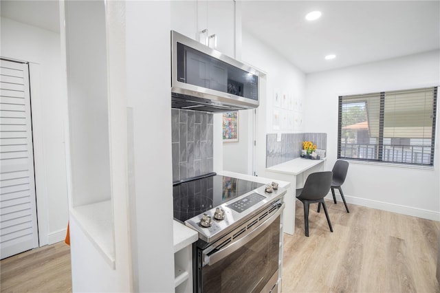 kitchen featuring white cabinetry, stainless steel appliances, tasteful backsplash, and light hardwood / wood-style flooring