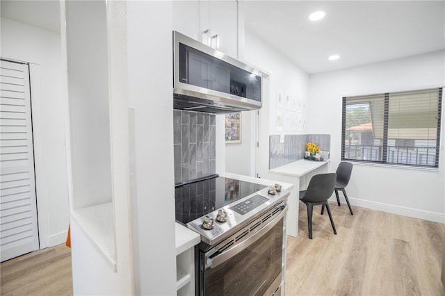 1515 Pinellas Bayway S Unit B28, Tierra Verde, FL 33715 - kitchen with stainless steel appliances, light wood-style flooring, light countertops, white cabinets, and baseboards