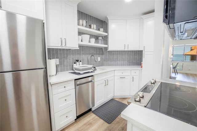 kitchen with decorative backsplash, white cabinetry, stainless steel appliances, and light hardwood / wood-style floors