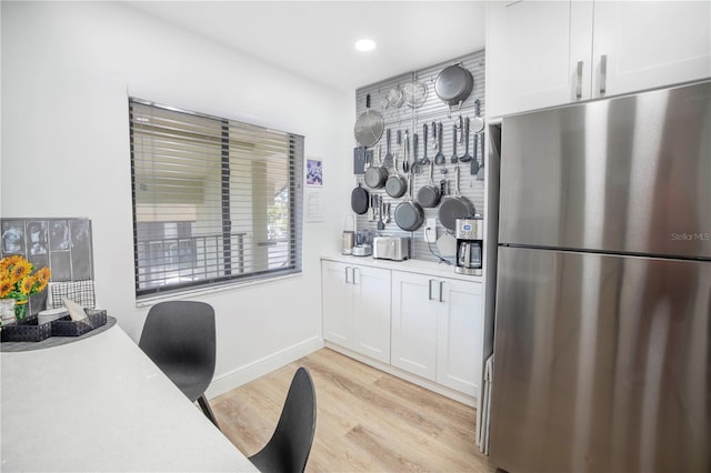 kitchen with light hardwood / wood-style floors, white cabinetry, and stainless steel refrigerator