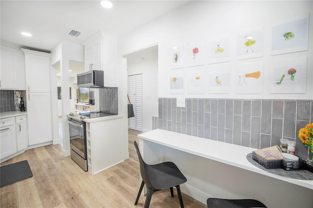 kitchen with white cabinetry, stainless steel appliances, tasteful backsplash, and light hardwood / wood-style flooring