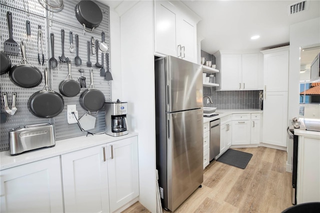 kitchen with appliances with stainless steel finishes, light wood-type flooring, and white cabinetry