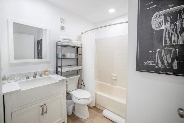 full bathroom featuring a baseboard heating unit, hardwood / wood-style floors, toilet, shower / bath combo with shower curtain, and vanity