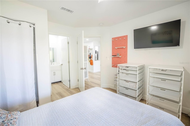 bedroom with light wood-type flooring and ensuite bath