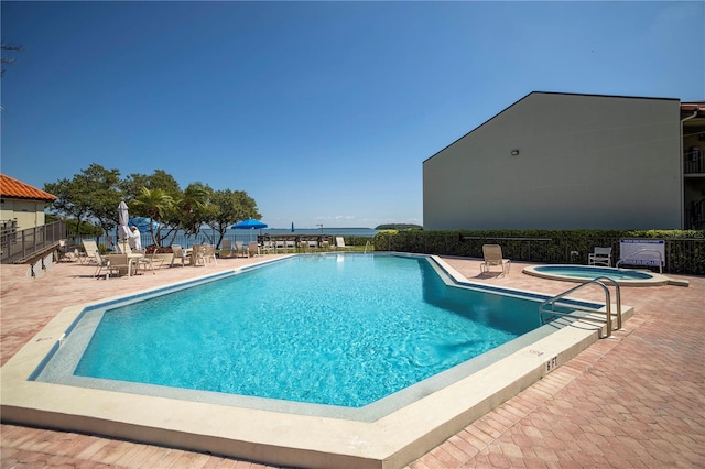 view of swimming pool featuring a patio area, a community hot tub, and a water view