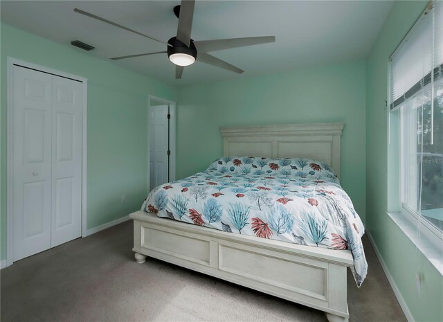 bedroom featuring multiple windows, ceiling fan, a closet, and dark carpet