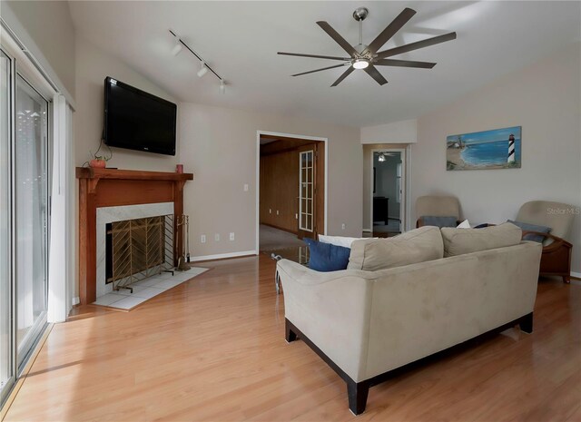 living room with ceiling fan, lofted ceiling, rail lighting, and light hardwood / wood-style flooring