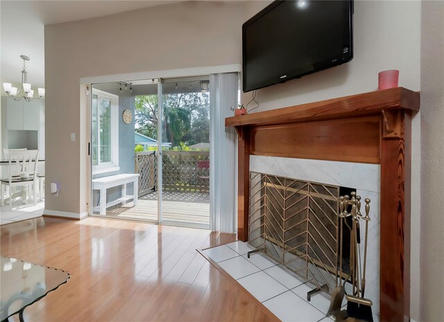 unfurnished living room featuring a premium fireplace, an inviting chandelier, and hardwood / wood-style flooring