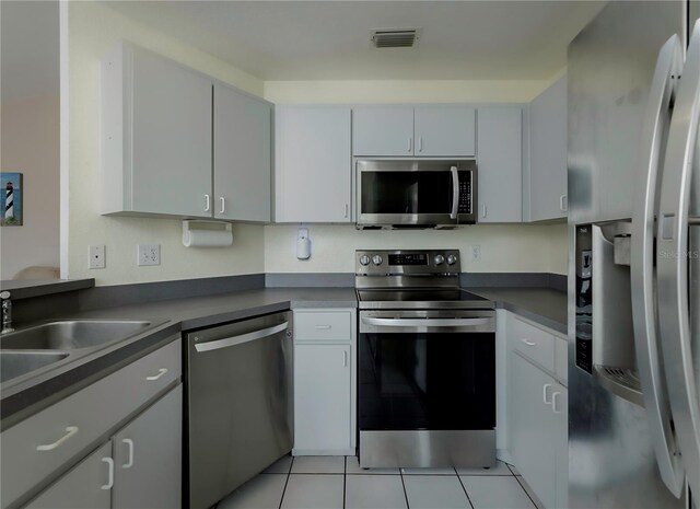 kitchen featuring white cabinets, light tile patterned floors, stainless steel appliances, and sink