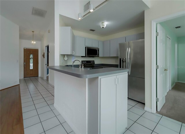 kitchen featuring stainless steel appliances, kitchen peninsula, pendant lighting, gray cabinets, and light tile patterned floors