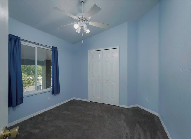 unfurnished bedroom featuring dark colored carpet, ceiling fan, lofted ceiling, and a closet