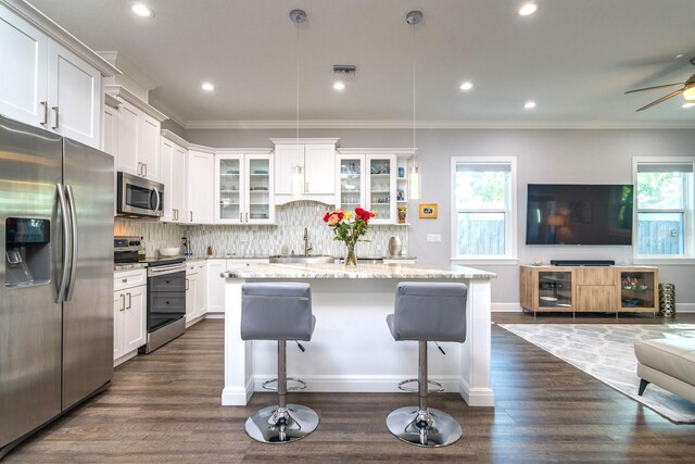 kitchen with a wealth of natural light, pendant lighting, stainless steel appliances, and a kitchen island