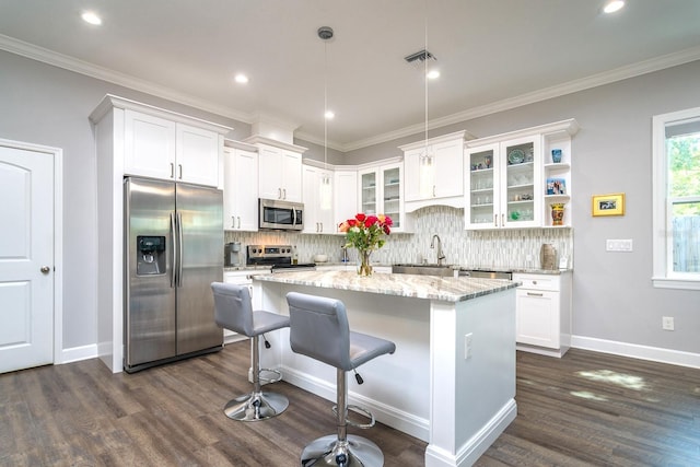 kitchen with a center island, white cabinetry, stainless steel appliances, and pendant lighting