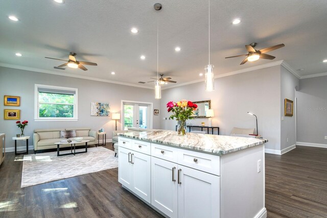 kitchen featuring white cabinets, light stone counters, dark hardwood / wood-style flooring, decorative light fixtures, and a center island