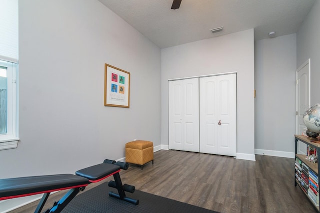 exercise room featuring dark wood-type flooring, a textured ceiling, and ceiling fan