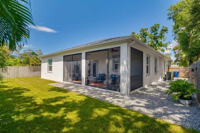 back of property featuring a patio, a sunroom, a lawn, and ceiling fan