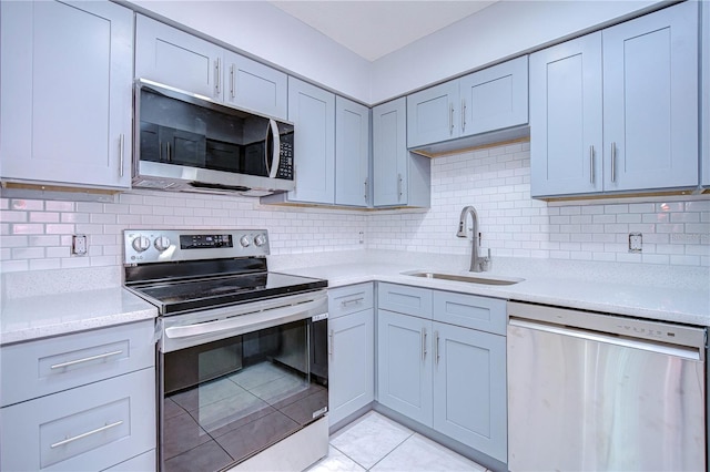 kitchen with backsplash, stainless steel appliances, sink, and light tile patterned floors