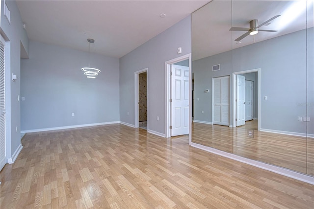 unfurnished room with a high ceiling, light wood-type flooring, and ceiling fan