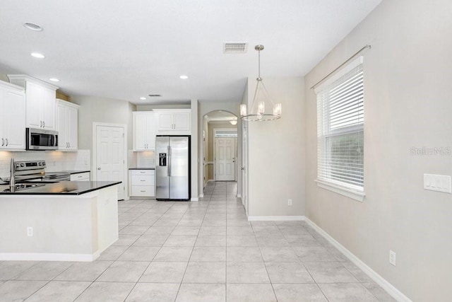 kitchen with white cabinetry, backsplash, stainless steel appliances, and hanging light fixtures