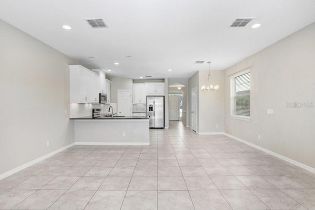 kitchen featuring sink, stainless steel appliances, pendant lighting, white cabinets, and a notable chandelier