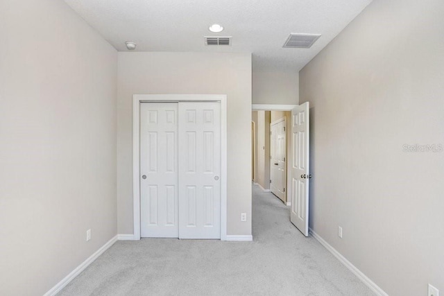 unfurnished bedroom featuring light carpet and a closet