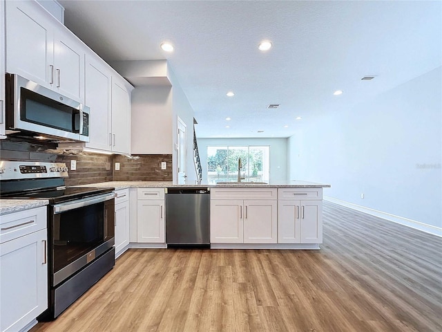 kitchen with stainless steel appliances, white cabinetry, light hardwood / wood-style floors, and sink