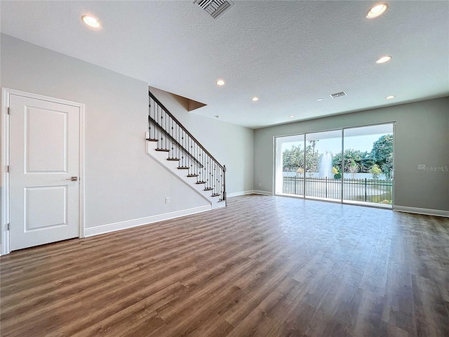 unfurnished living room with a textured ceiling and dark hardwood / wood-style floors