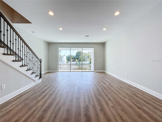 unfurnished living room featuring a textured ceiling and dark hardwood / wood-style floors