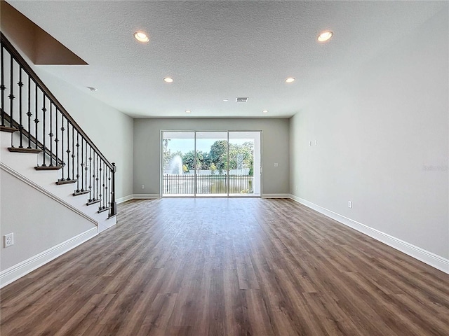 unfurnished living room with a textured ceiling and dark hardwood / wood-style floors