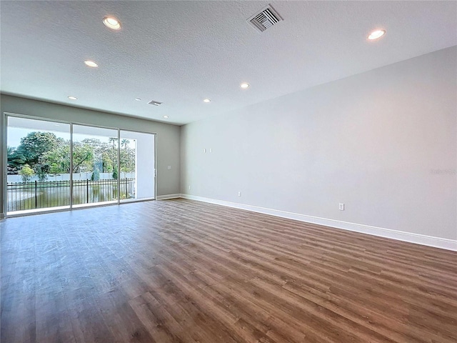 spare room with dark hardwood / wood-style floors, a water view, and a textured ceiling