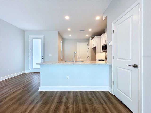 kitchen with light stone countertops, kitchen peninsula, dark hardwood / wood-style flooring, sink, and white cabinetry