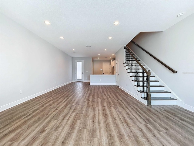 unfurnished living room with a textured ceiling and light hardwood / wood-style flooring