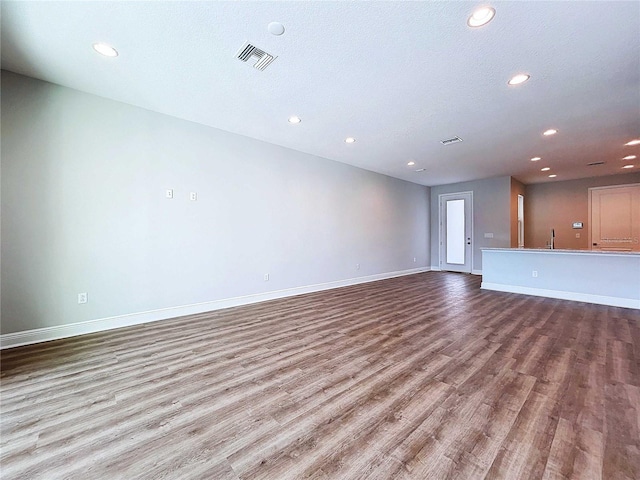 unfurnished living room with light wood-type flooring and a textured ceiling