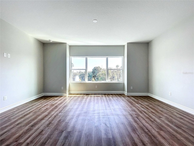 empty room with dark hardwood / wood-style flooring and a textured ceiling