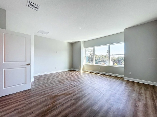 unfurnished room with dark hardwood / wood-style flooring and a textured ceiling