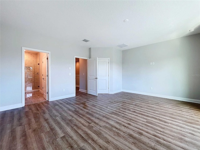 unfurnished bedroom featuring a textured ceiling, dark hardwood / wood-style floors, and ensuite bath