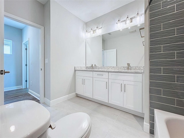 bathroom featuring a bathtub, vanity, tile patterned floors, toilet, and a textured ceiling