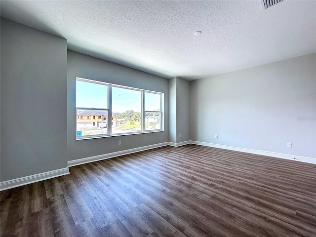 spare room with a textured ceiling and dark hardwood / wood-style floors