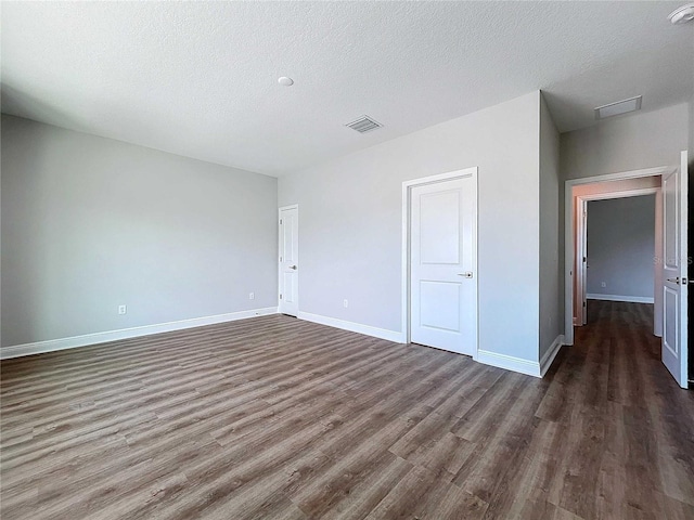 unfurnished bedroom featuring a textured ceiling and dark wood-type flooring