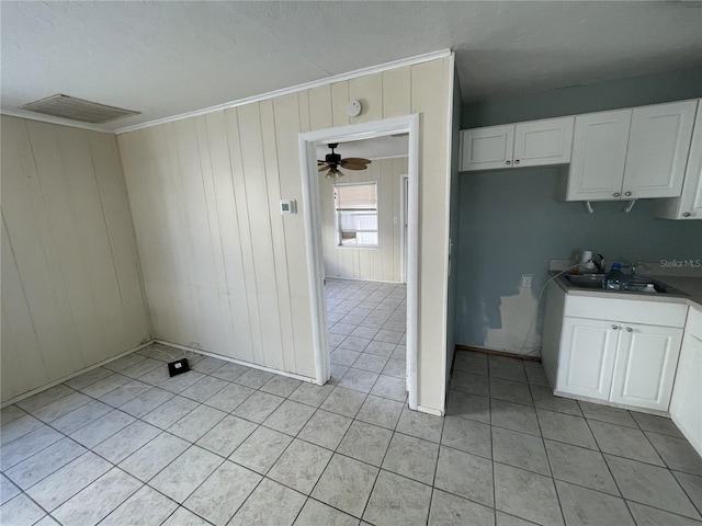 kitchen featuring white cabinetry, ceiling fan, sink, wood walls, and light tile patterned flooring