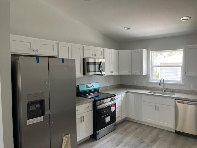 1740 Magnolia Ave, Bartow, FL 33830 - kitchen with sink, white cabinetry, stainless steel appliances, light hardwood / wood-style floors, and vaulted ceiling