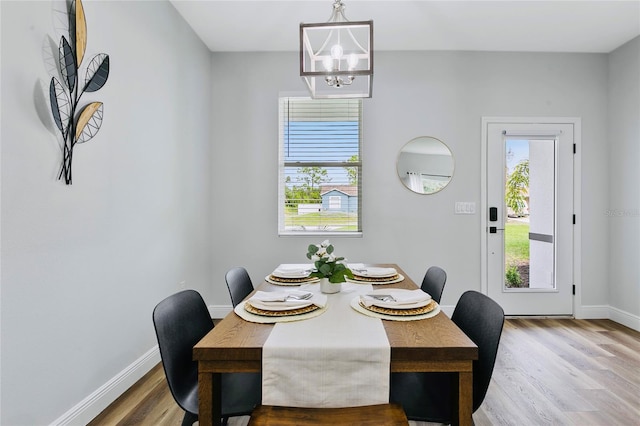 dining area featuring wood-type flooring and an inviting chandelier