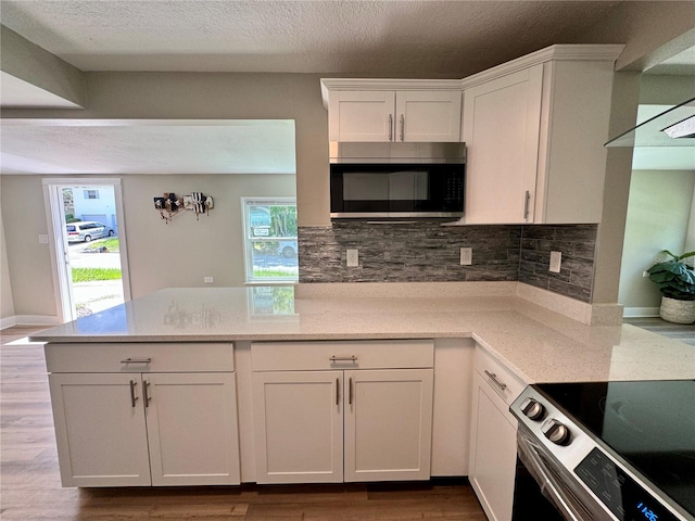 kitchen with decorative backsplash, light hardwood / wood-style flooring, white cabinetry, and stainless steel appliances