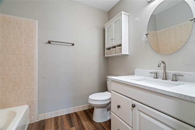 full bathroom with vanity, washtub / shower combination, hardwood / wood-style flooring, and toilet