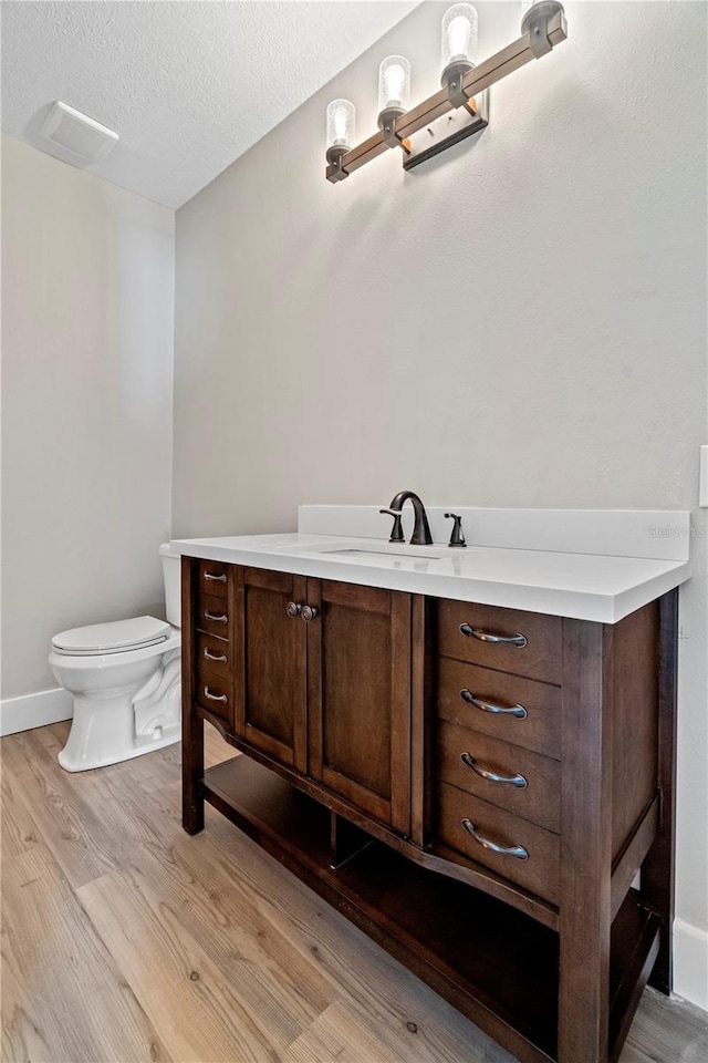 bathroom with vanity, a textured ceiling, hardwood / wood-style flooring, and toilet