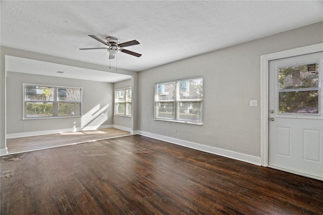 unfurnished living room featuring a textured ceiling, dark hardwood / wood-style flooring, and a wealth of natural light