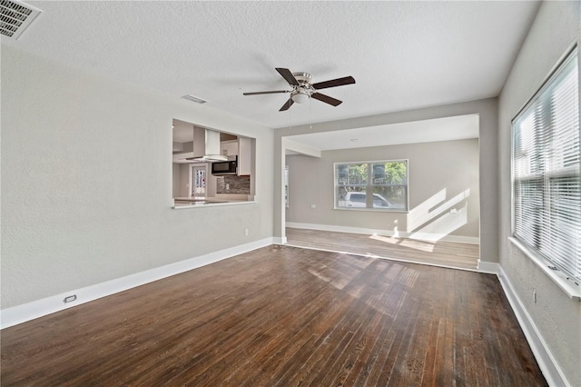 unfurnished living room with a textured ceiling, dark hardwood / wood-style floors, and ceiling fan